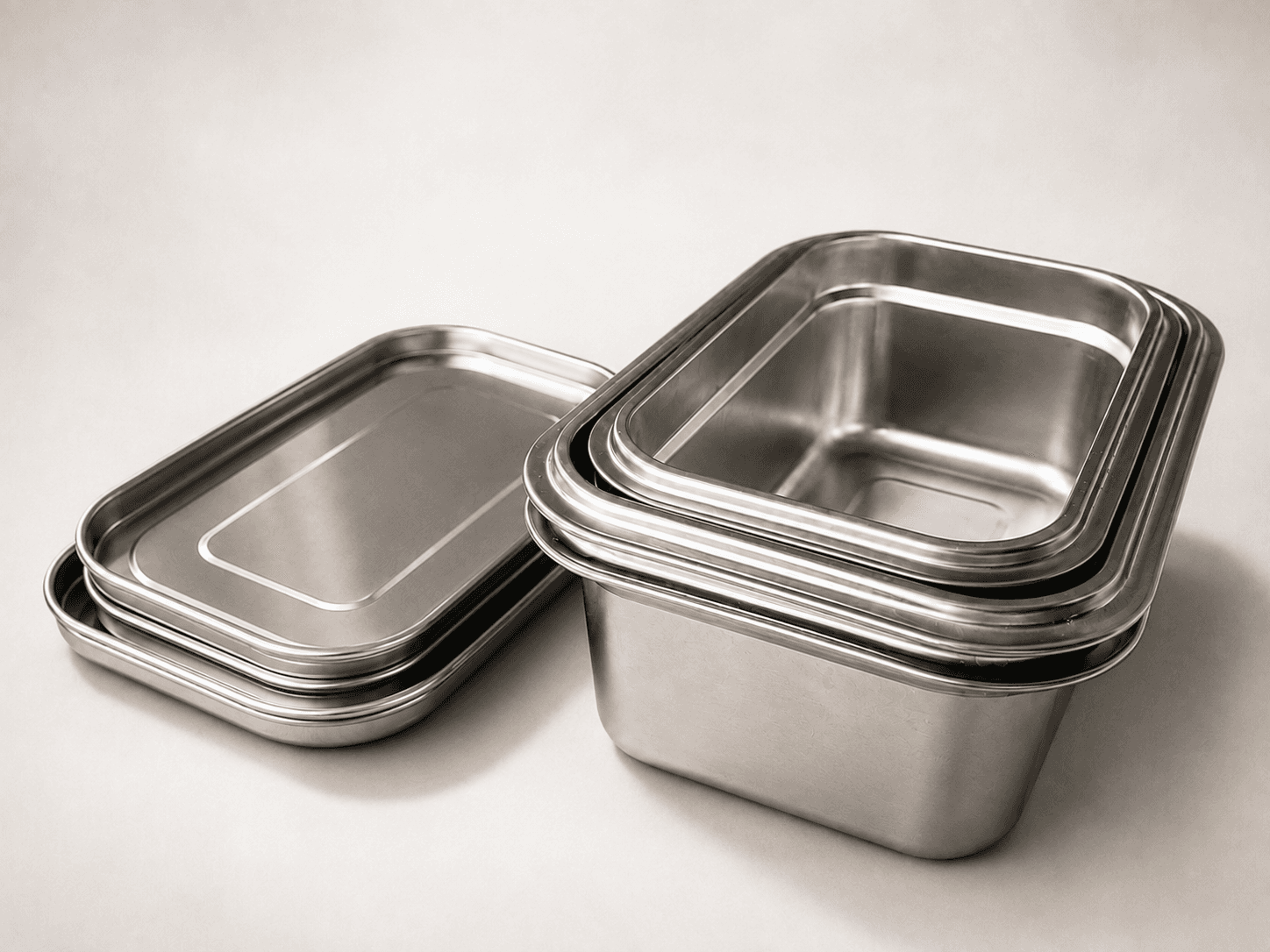 Several Loopware stainless steel containers nested inside one another, with their flat steel lids stacked separately alongside